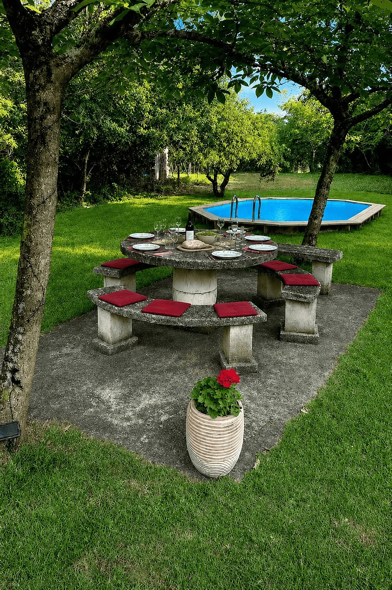 La table de pierre et la piscine, sous les arbres